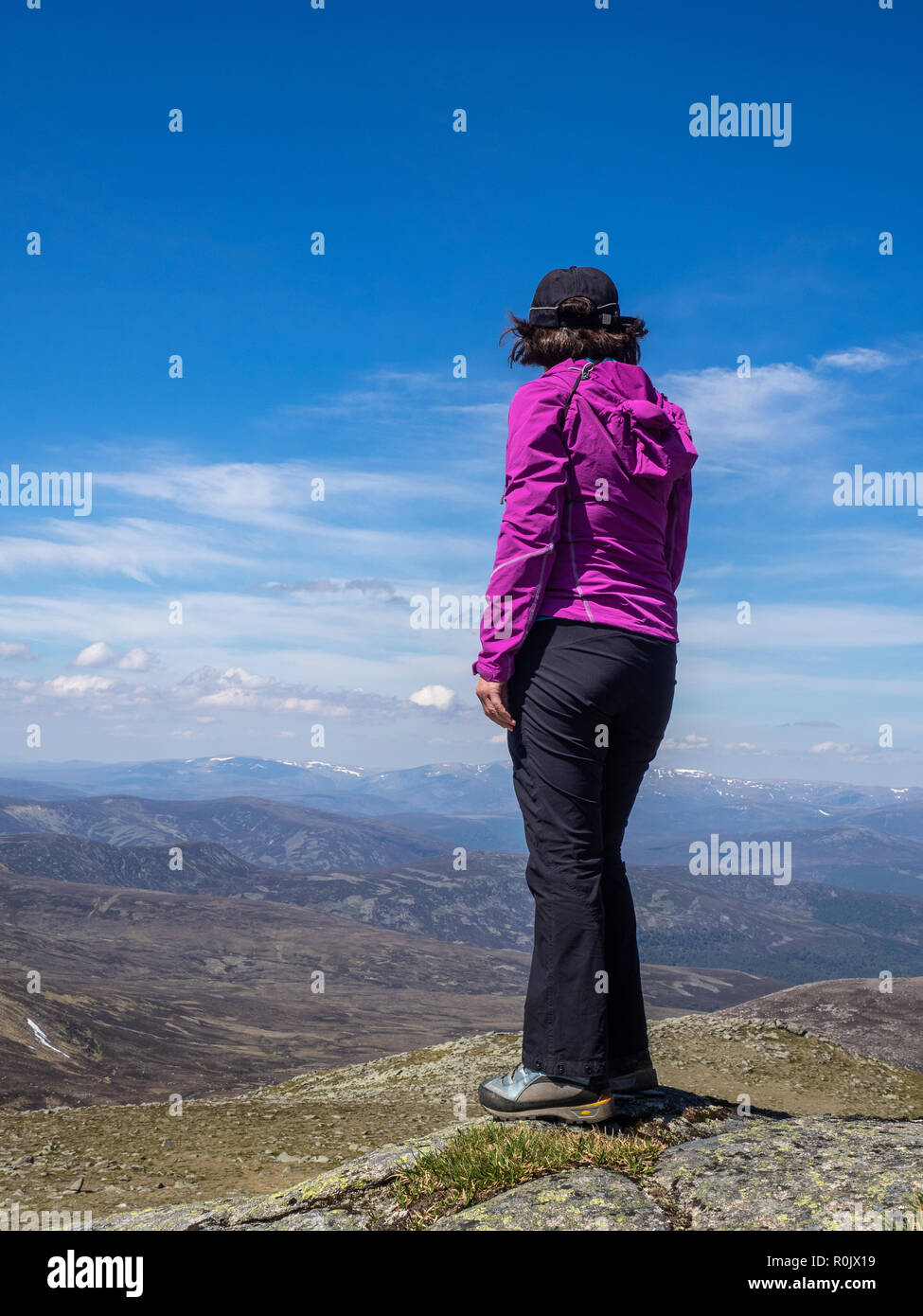 Eine reife Lady mit Blick auf die schottische Landschaft von einem Aussichtspunkt hoch auf den Hügeln bei einer Wanderung Stockfoto