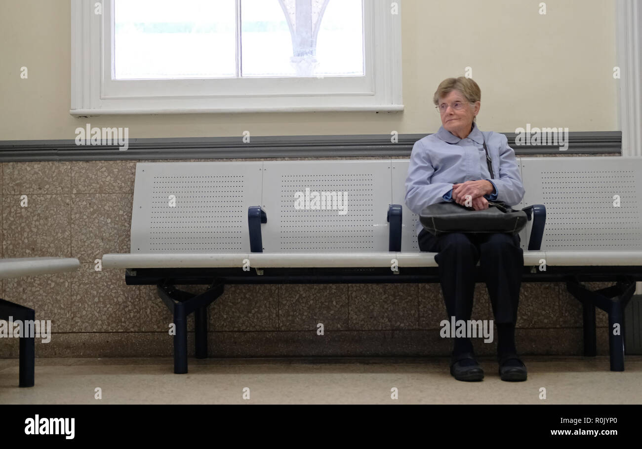 Eine pensionierte Dame in einem Wartezimmer sitzen auf einem Bahnhof. Stockfoto
