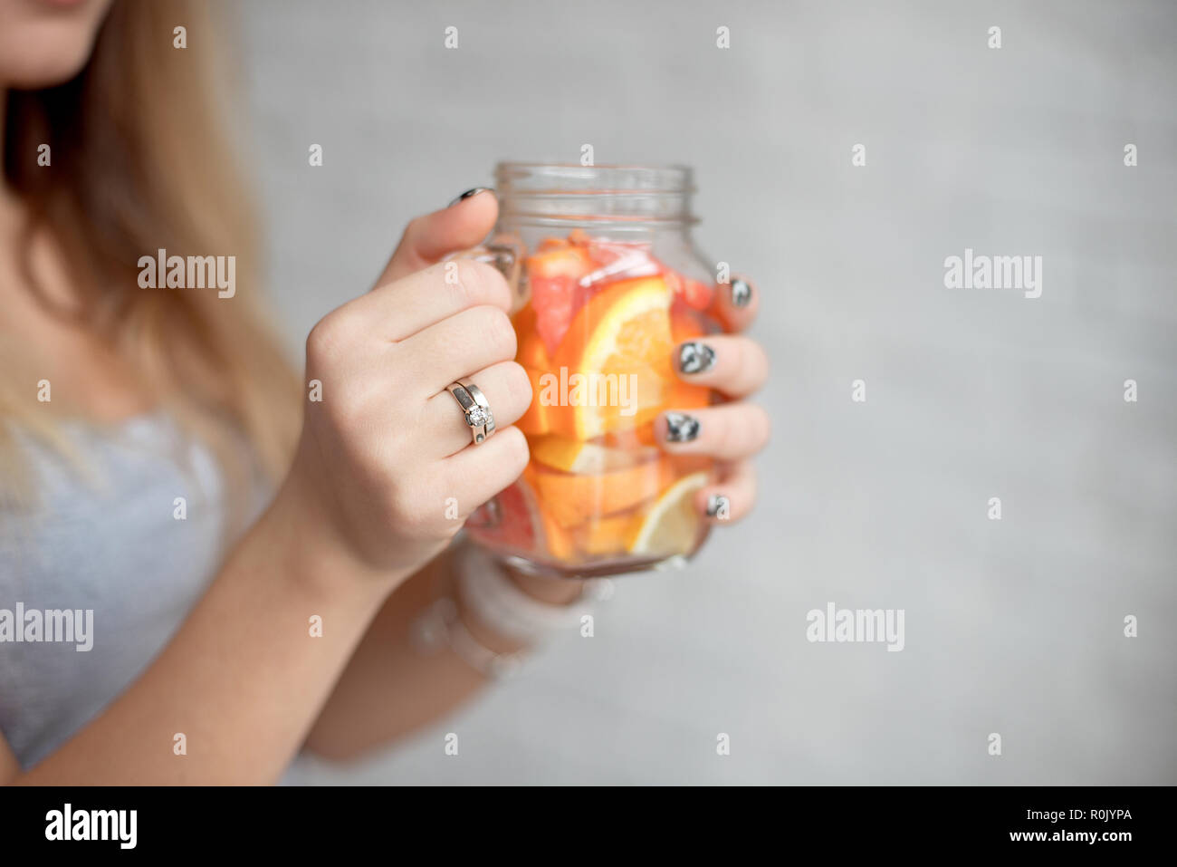 Close-up glückliche Frau mit einem Glas frischen Sommer Limonade mit Stroh. Kaukasische Mädchen 20-25 Jahre alt Zuhause gegen Mauer Hintergrund. Stockfoto