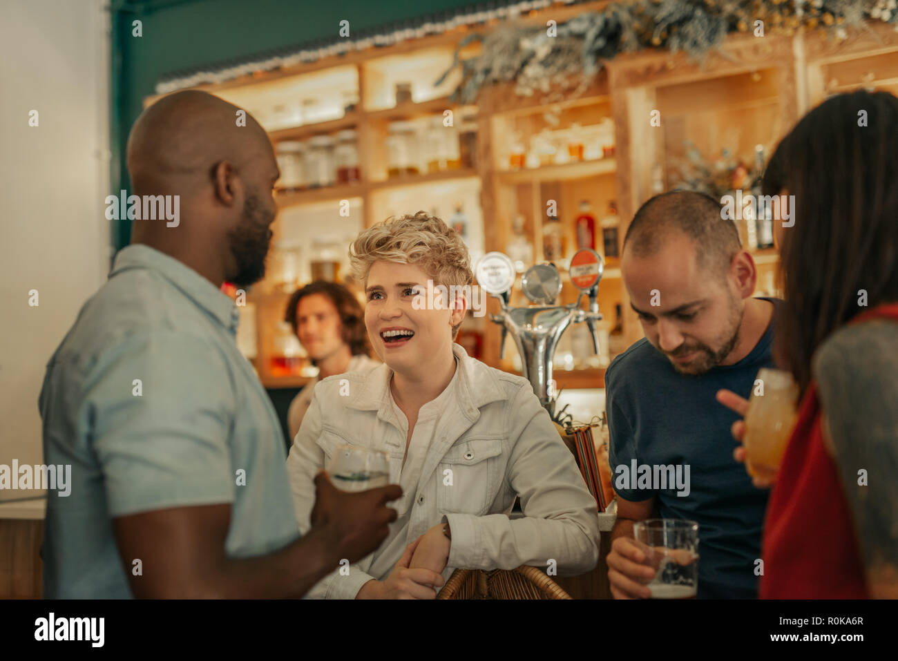 Gruppe von verschiedenen jungen Freunde lachen und reden über Cocktails, während gemeinsam in eine trendige Bar Stockfoto