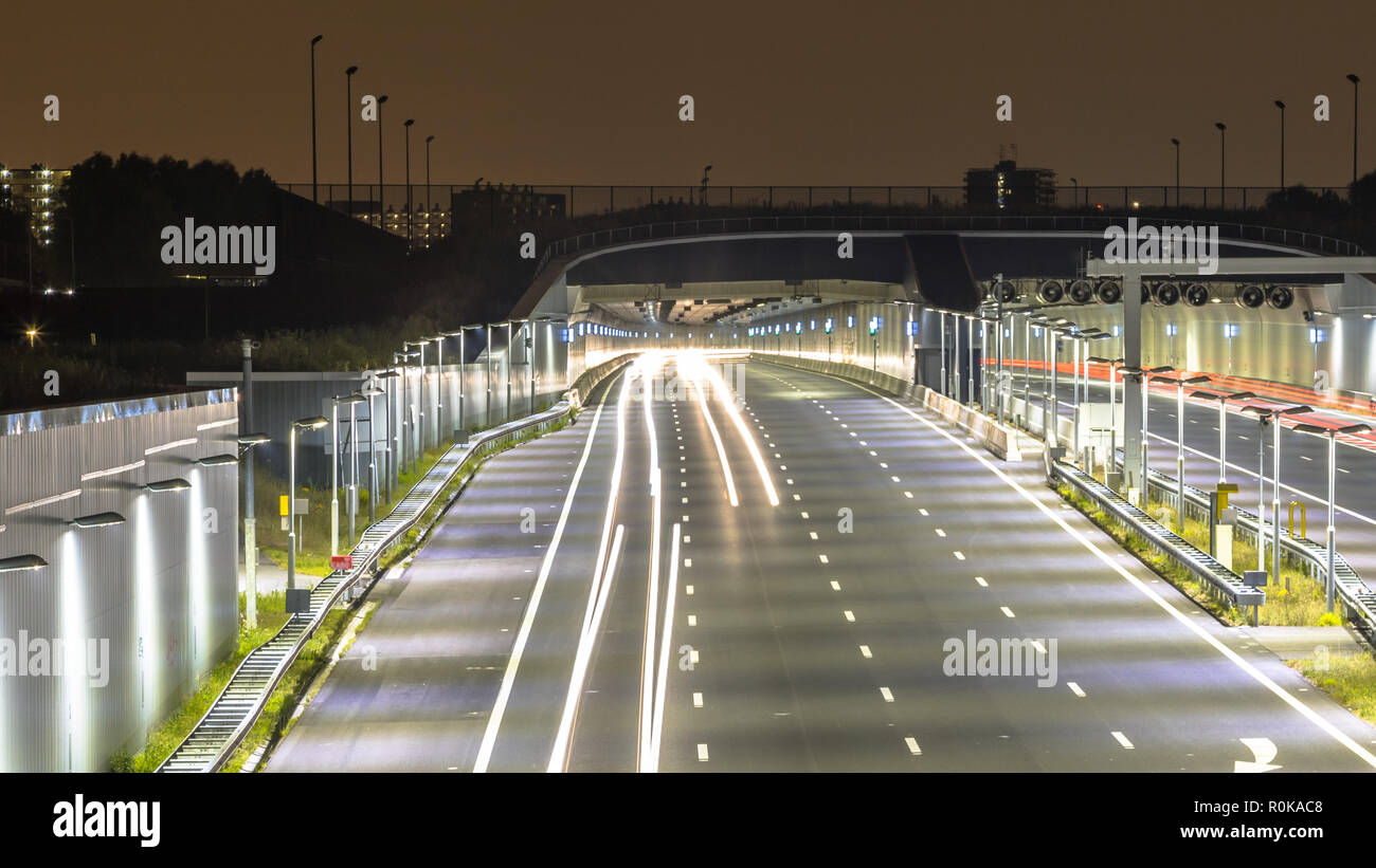 Autobahn mit Tunnel Eingang bei Nacht mit unscharfen Auto Scheinwerfer durch lange Belichtung Stockfoto