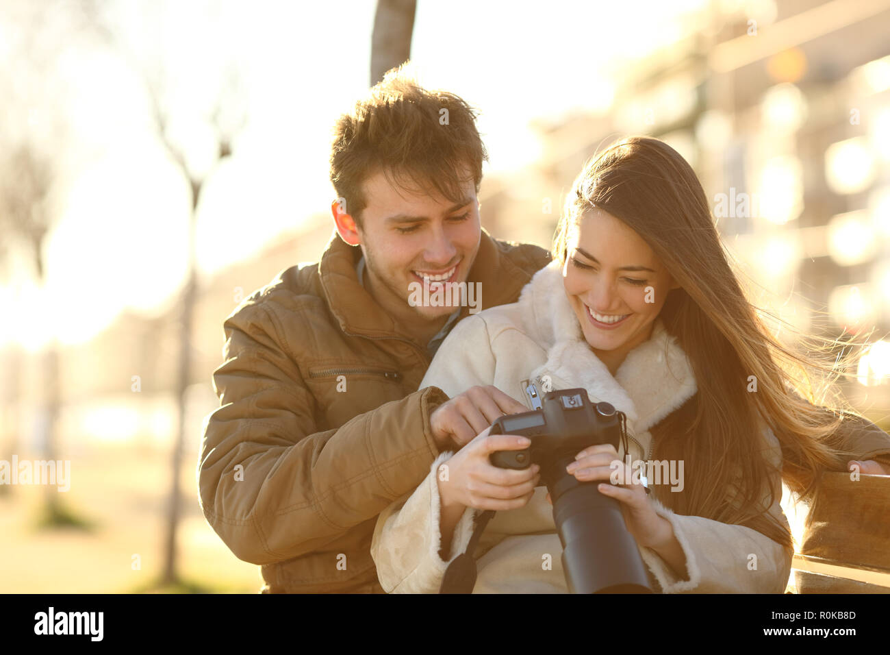 Glückliches Paar prüfen Fotos auf eine DSLR-Kamera sitzen auf einer Bank in einem Park Stockfoto