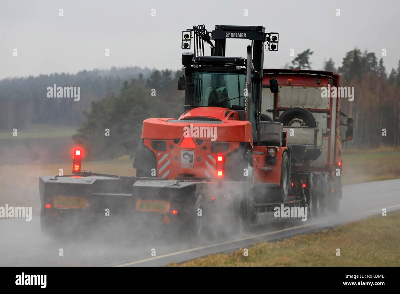 Salo, Finnland - 2 November, 2018: Auflieger von Kosken Autokeskus schleppt große Gabelstapler in den regnerischen, geringe Sichtbarkeit Wetterbedingungen. Ansicht von hinten. Stockfoto