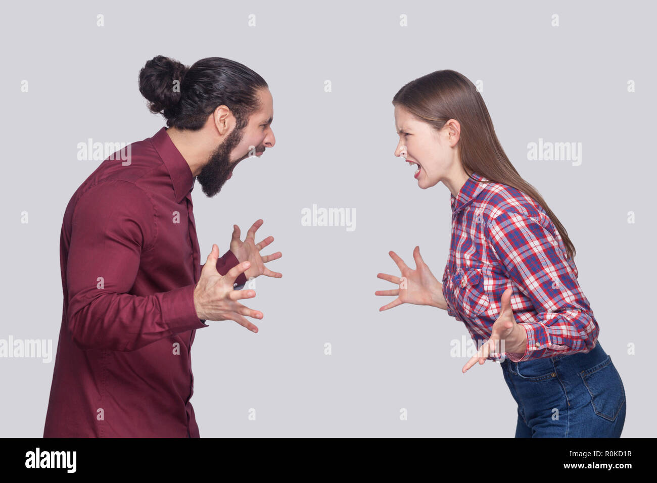 Profil Seitenansicht Portrait von Angry bärtiger Mann mit schwarzem Haar gesammelt und die Frau in der lässigen Stil stehen, suchen und Schreien an einander. ind Stockfoto