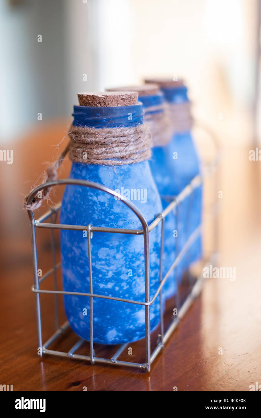 Drei blaue Flaschen mit Naturkorken, mit Sisal hanf Garn in einem Draht container gebunden. Stockfoto