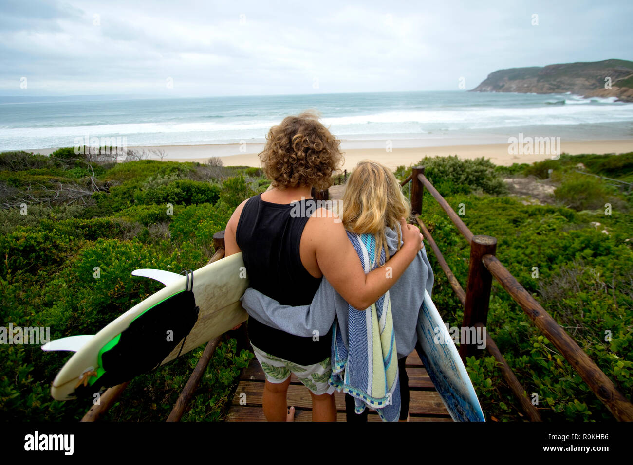 Surfer zu Fuß auf den Strand von einem Laufsteg Stockfoto