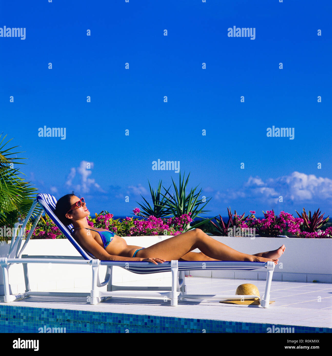Junge Frau mit blauen Bikini Sonnenbaden auf Sonnenliegen am Pool, Guadeloupe, Französisch Westindien, Stockfoto