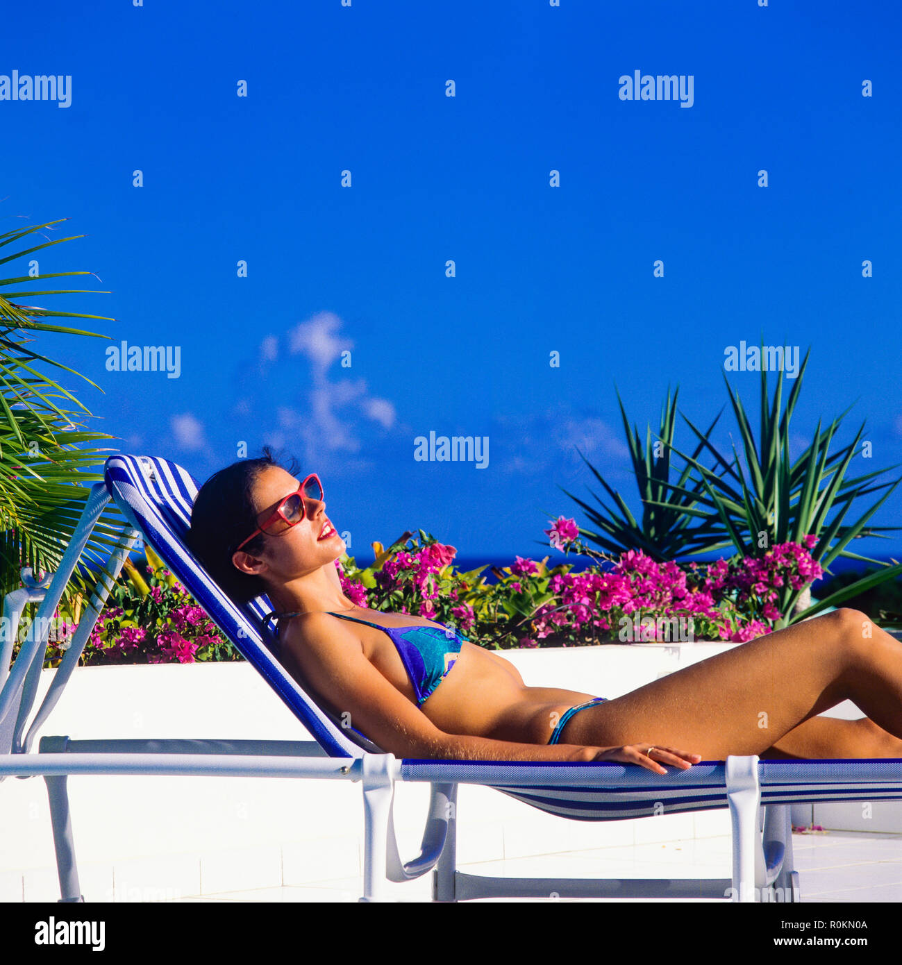 Junge Frau mit blauen Bikini Sonnenbaden auf Sonnenliegen am Pool, Guadeloupe, Französisch Westindien, Stockfoto