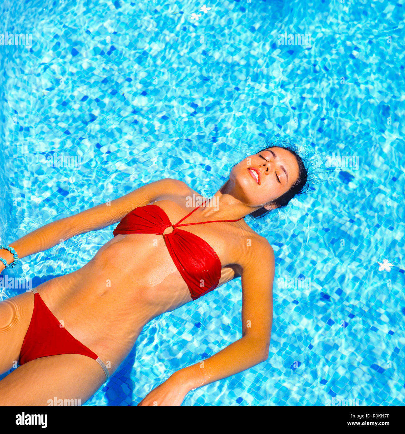 Junge Frau mit roten Bikini schwimmt auf Wasser im Schwimmbad, Guadeloupe, Französisch Westindien, Stockfoto