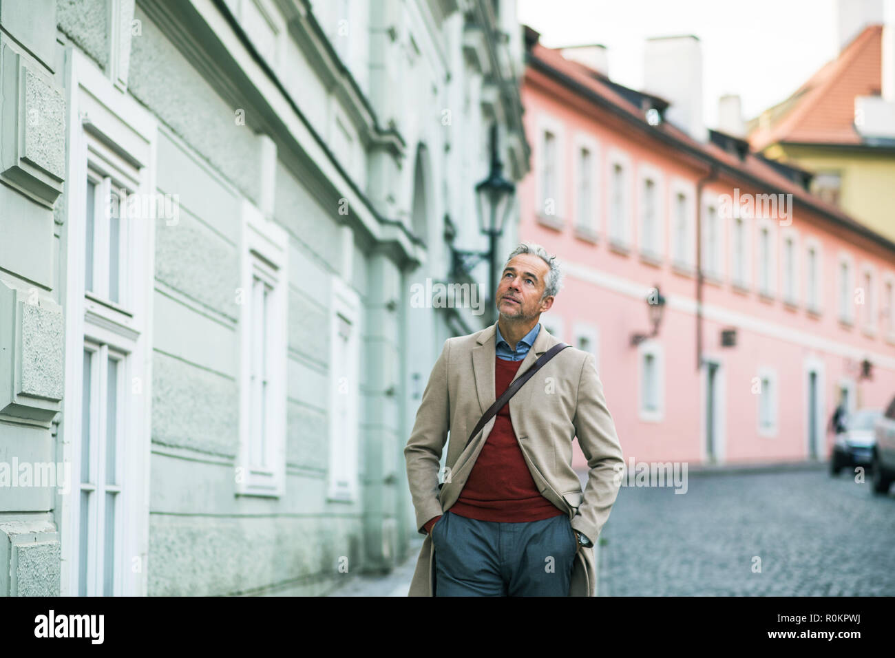 Eine ausgereifte Geschäftsmann zu Fuß auf einer Straße in Prag, die Hände in den Taschen. Stockfoto
