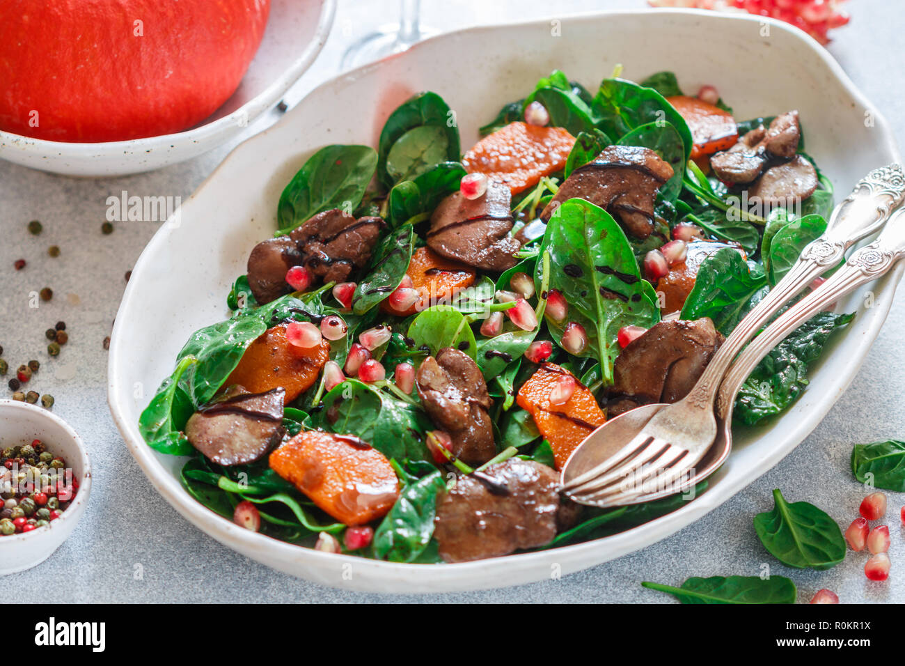 Warme Spinat Salat mit Huhn Leber, gebackener Kürbis und Granatapfel mit Gewürzen und Balsamico. Leckeres Essen für Feinschmecker. Selektiver Fokus Stockfoto