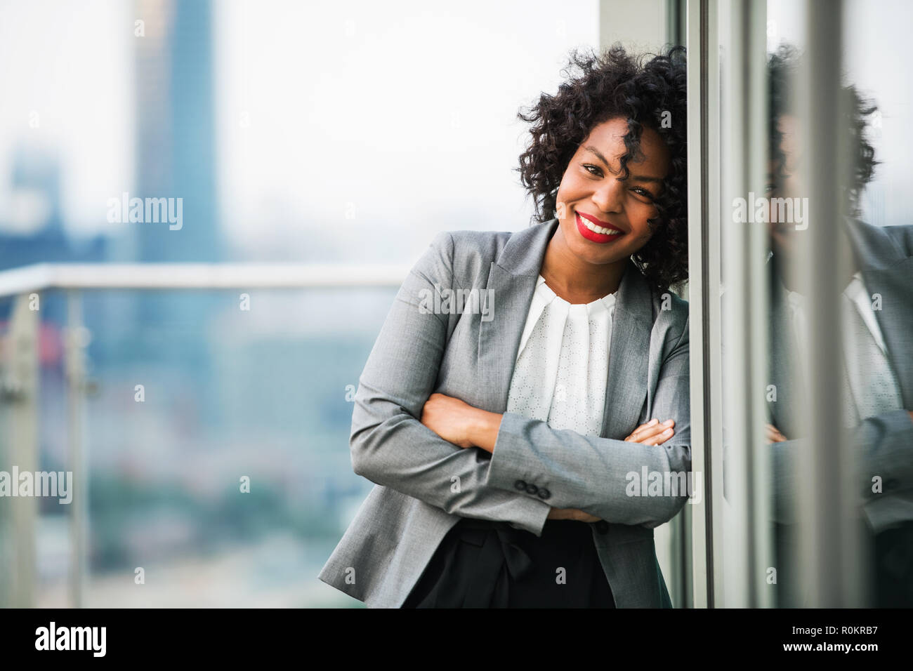 Das Porträt einer Geschäftsfrau, die auf eine Terrasse, die Arme verschränkt. Stockfoto