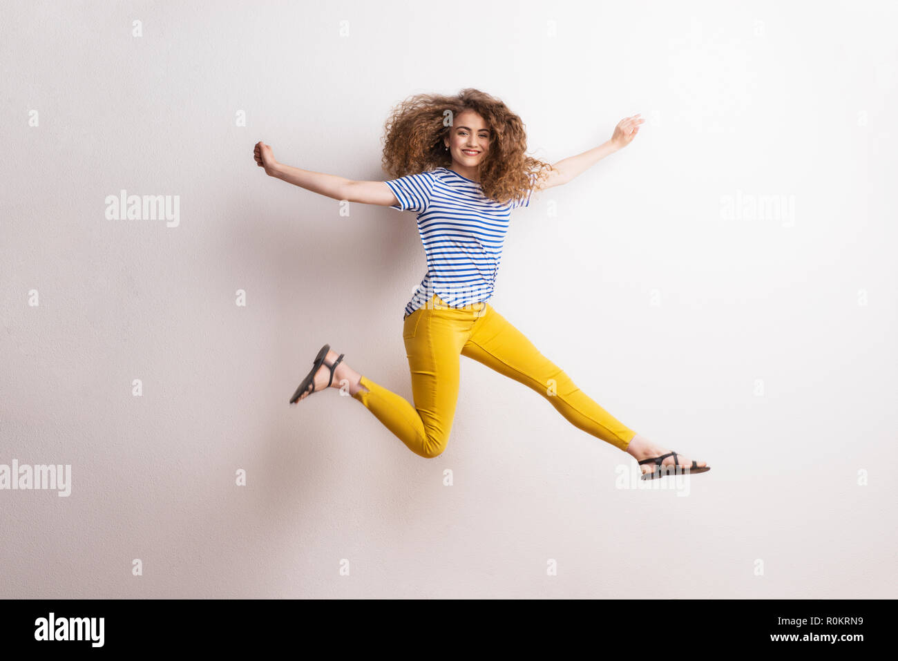 Junge schöne fröhliche Frau mit langen, lockigen Haar im Studio, springen. Stockfoto