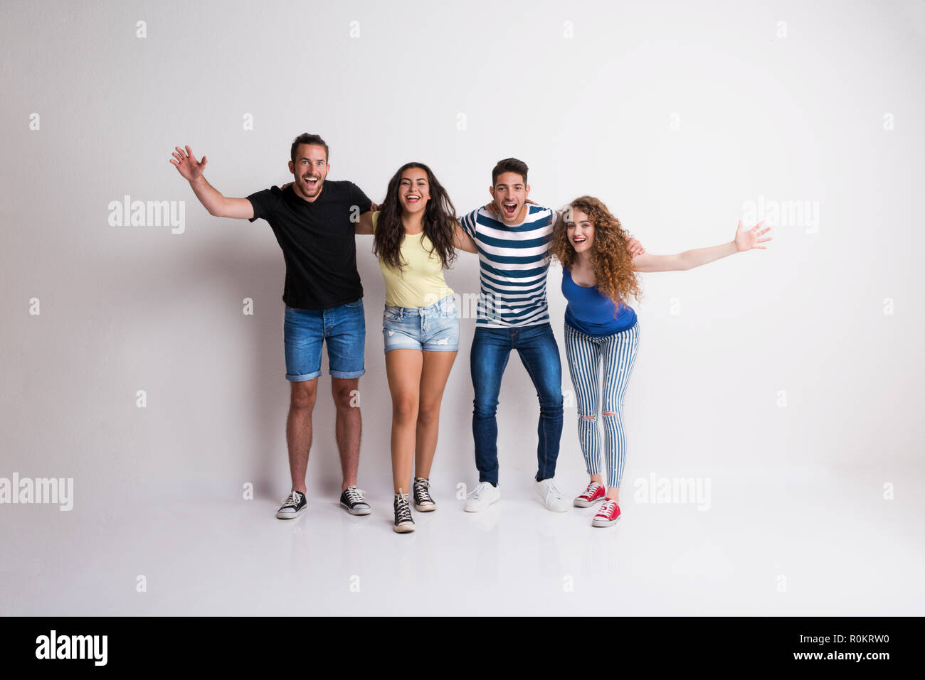 Portrait von freudige junge Gruppe von Freunden stehen Arm in Arm in einem Studio. Stockfoto
