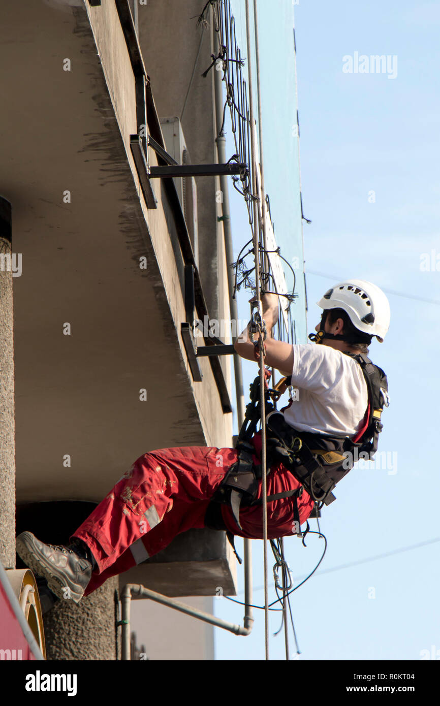 Belgrad, Serbien - November 19, 2018: industriekletterer am Seil hängend während der Installation von Werbebanner auf einer Bilding, Low Angle View Stockfoto