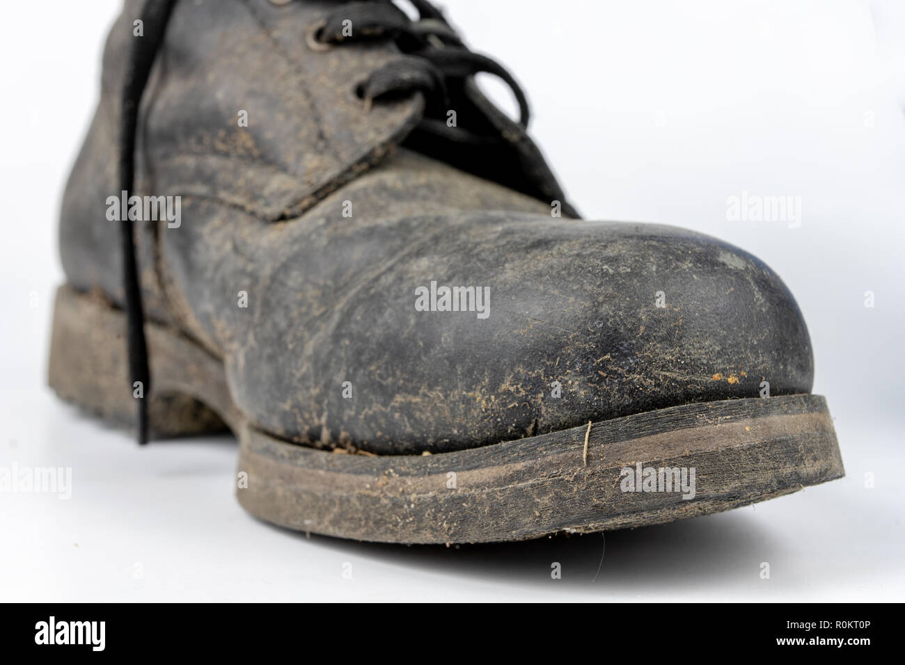 Alte schwarze schmutzige Schuhe. Leder militärischen Schuhe auf einem weißen Tisch. Hellen Hintergrund. Stockfoto