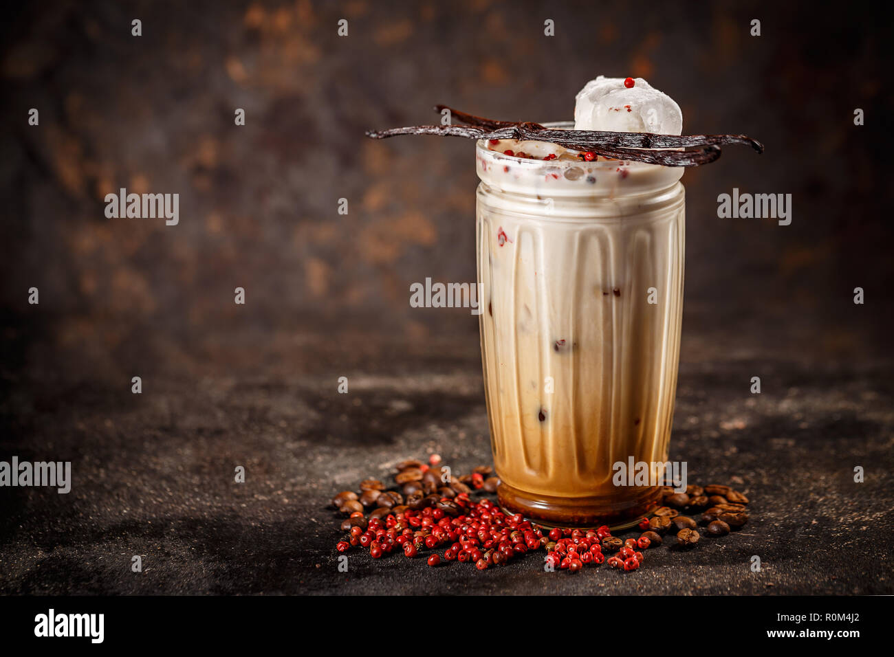 Eiskaffee mit Milch in hohes Glas gewürzt mit rosa Pfeffer und Vanille Stockfoto