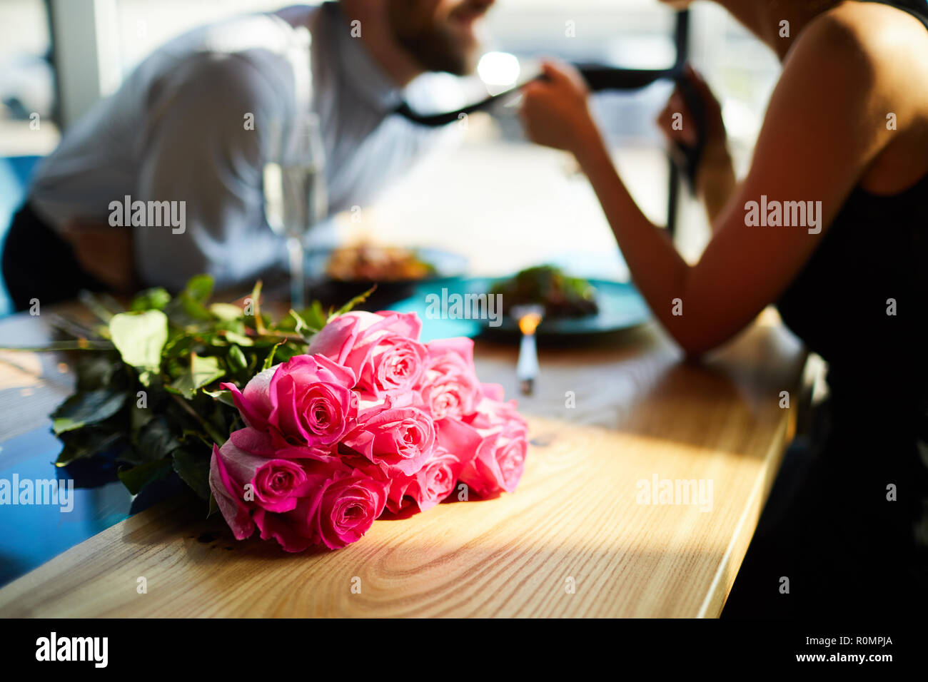 Frische Romantische Rosen auf dem Tisch auf dem Hintergrund der Amourösen Mann und Frau Flirten Stockfoto