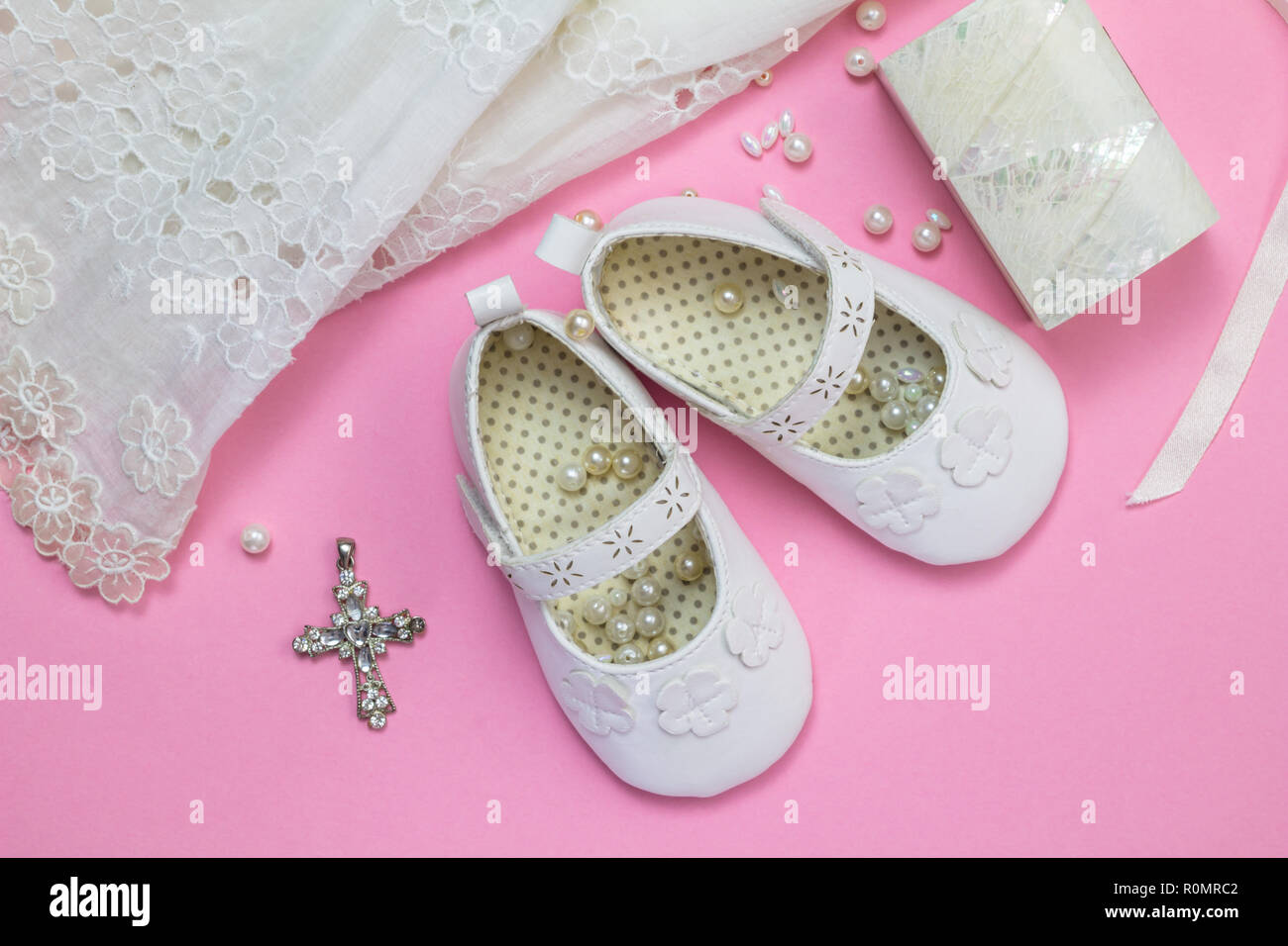 Taufe Kleid, Schuhe, Kristall Kreuz Anhänger, Perlen und Perlmutt box auf rosa Hintergrund isoliert - Ansicht von oben Foto von baby girl Christe Stockfoto