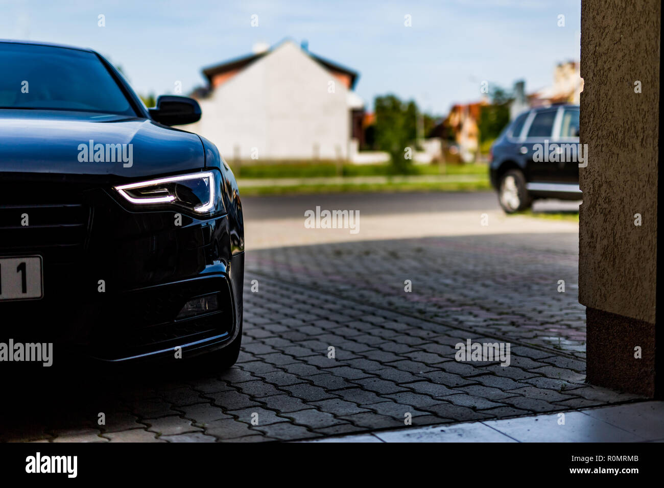 Schwarzes Auto mit Beleuchtung auf, vor dem Haus an der Einfahrt Stockfoto