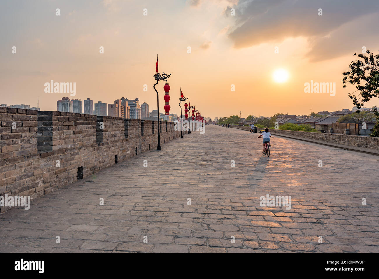 Xi'an, Provinz Shaanxi, China - Aug 8, 2018: Touristen Wandern und Reiten Fahrrad auf die Stadt befestigten Mauer bei Sonnenuntergang Stockfoto