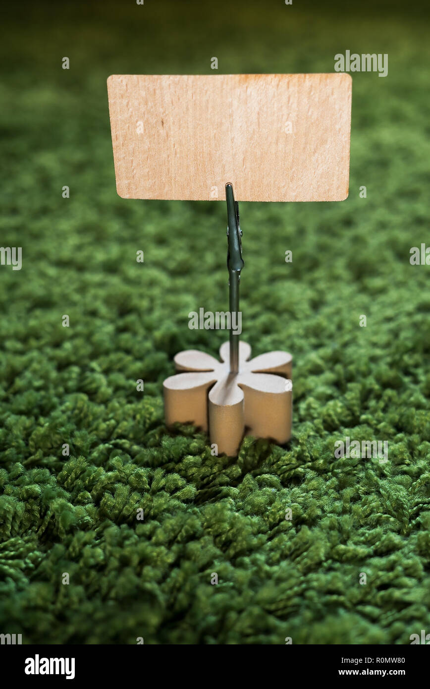 Clip Kartenhalter mit Holz- Blume auf grünem Gras Teppich Holding eine natürliche Holz- Ankündigung Anzeige mit leeren Raum für Text und kopieren Stockfoto