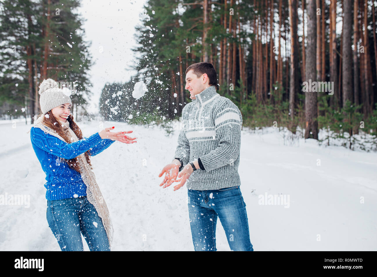 Schneeballschlacht. Winter-Paare, die Spaß im Schnee im Freien spielen. Junge fröhliche multiethnische Brautpaar. Stockfoto
