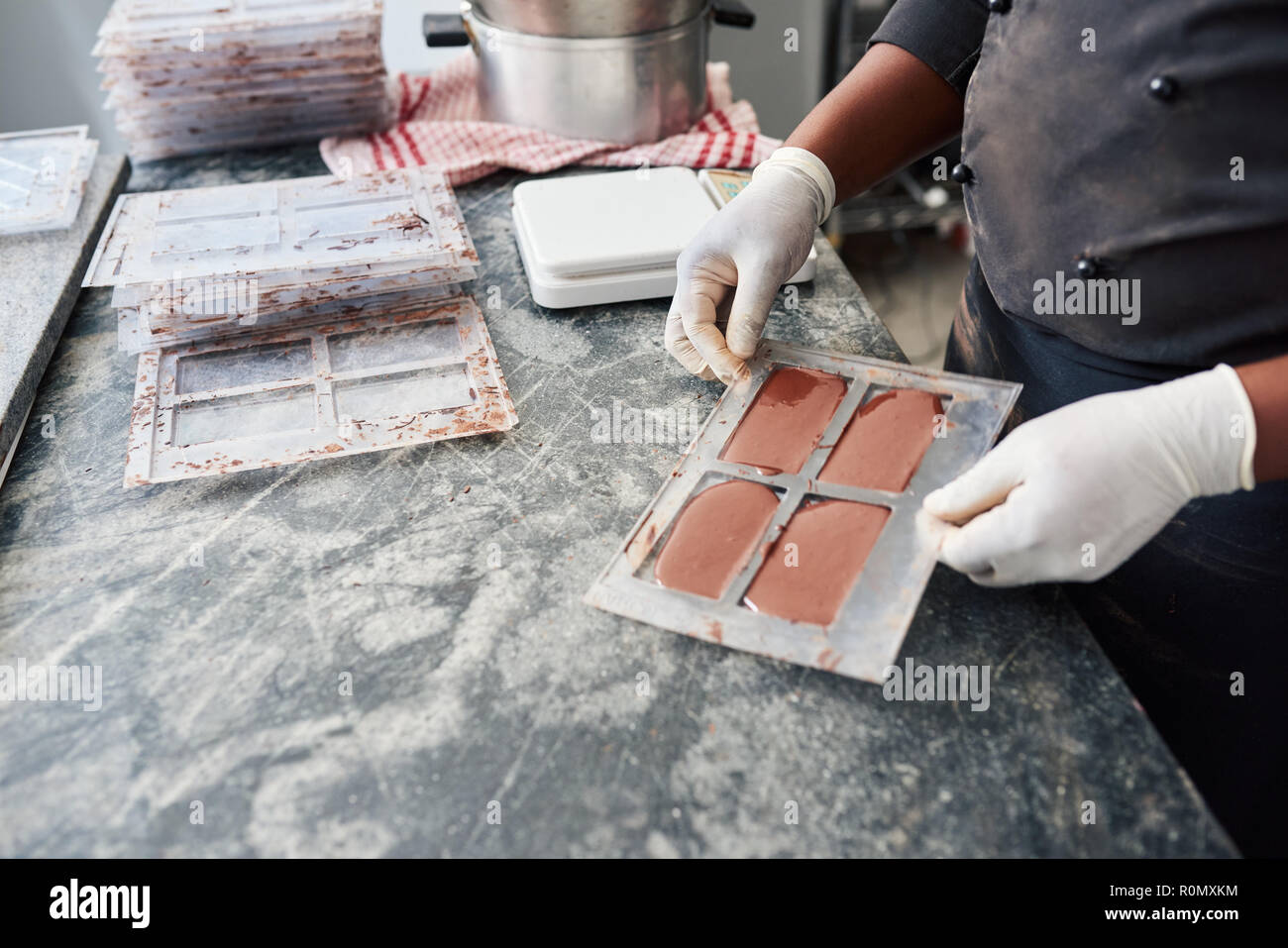 Arbeitnehmer, die eine Bar voller Schimmel geschmolzene Schokolade Stockfoto