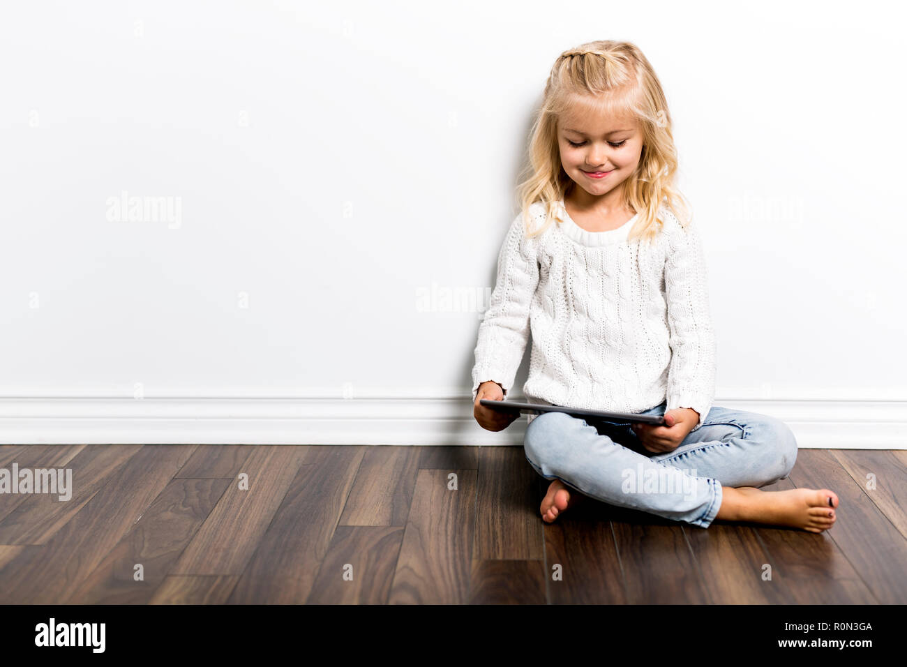 Ein Kind mit Tablet liegen auf dem Boden. Mädchen spielen Laptop Stockfoto