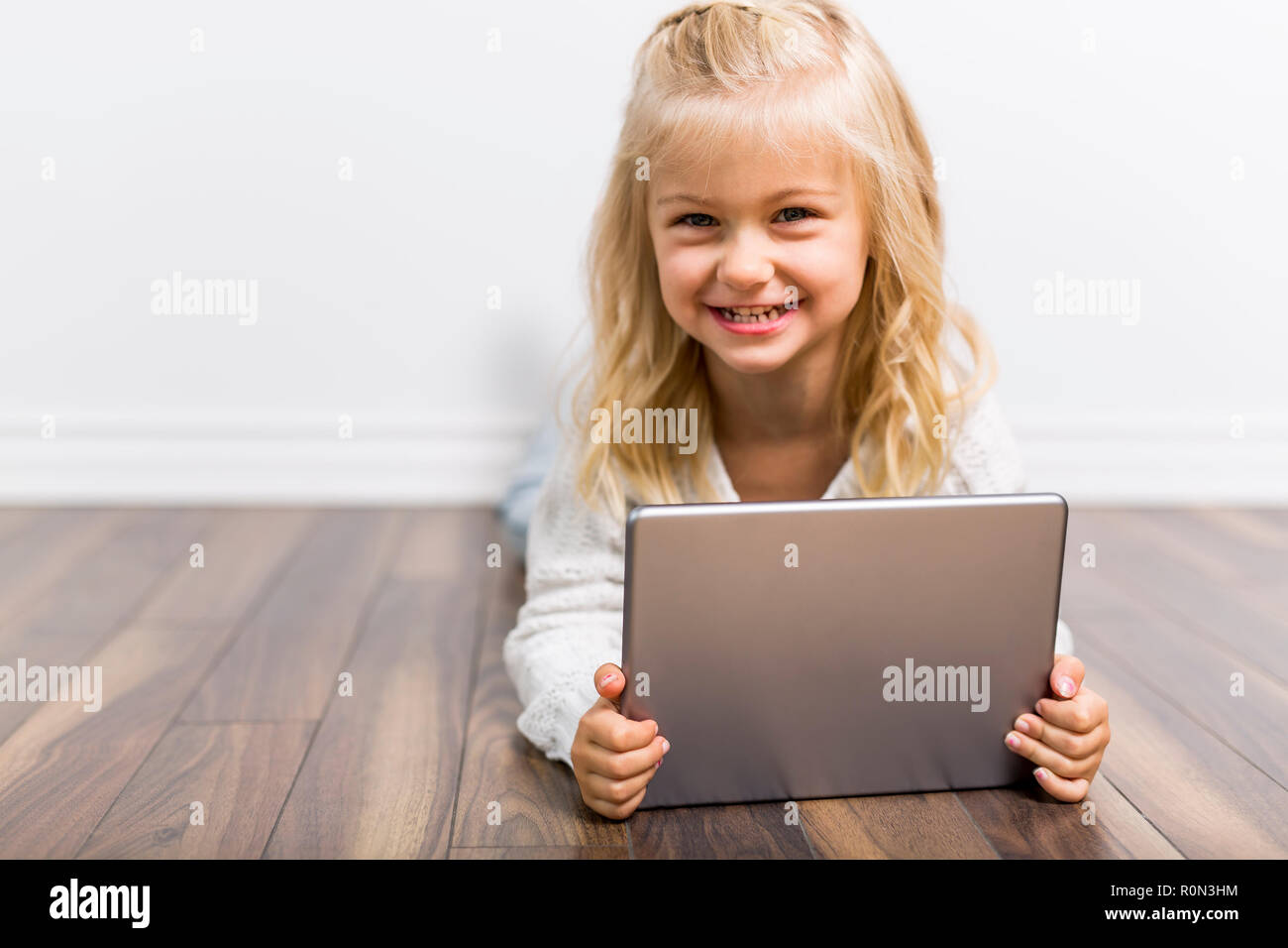 Ein Kind mit Tablet liegen auf dem Boden. Mädchen spielen Laptop Stockfoto