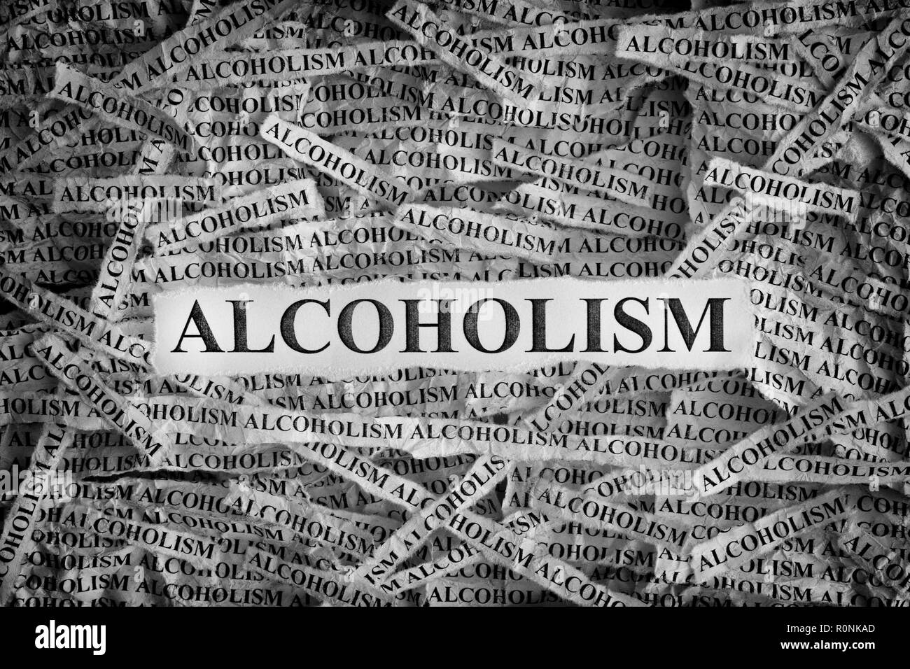 Alkoholismus. Papierreste mit dem Wort Alkoholismus. Konzept Bild. Schwarz und Weiß. Nahaufnahme. Stockfoto