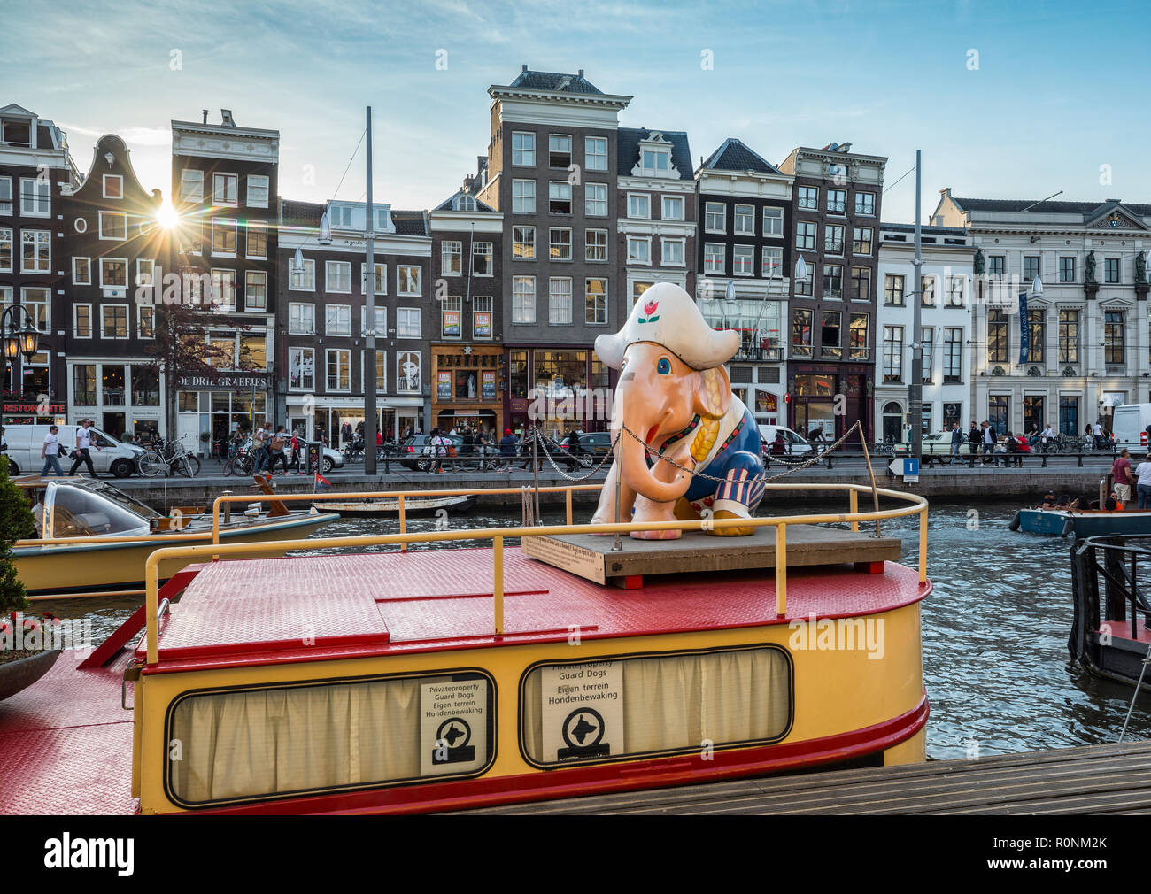 Elefant Skulptur (Dutch Lady von Thammakit Thamboon) auf dem Boot und Sun si zwischen Gebäuden in Amsterdam, glänzend Stockfoto