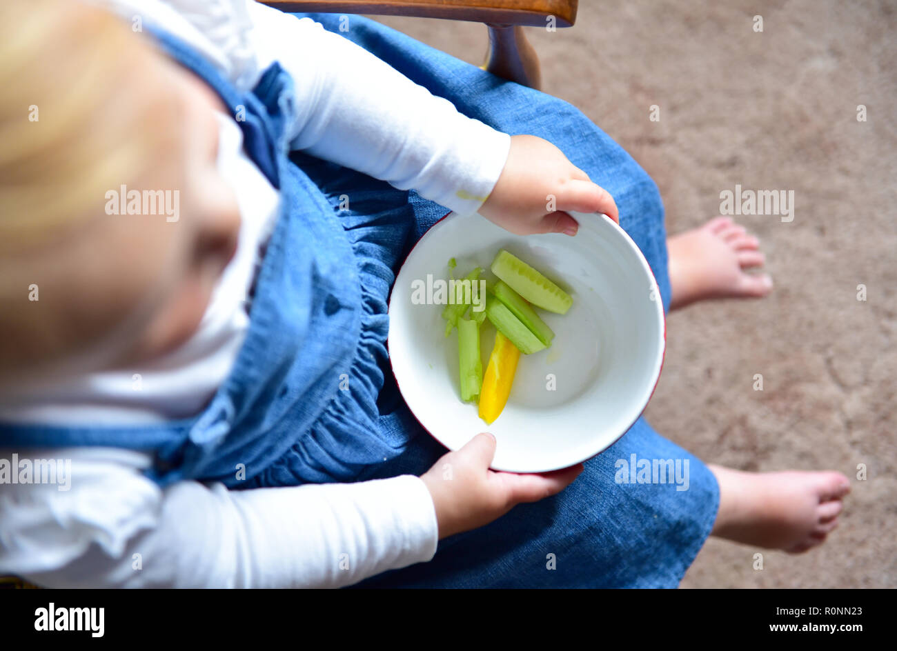 Junge Baby Kleinkind Mädchen im Alter von 2 Jahren essen gesunde Ernährung von frischem Paprika und Gurken snack Foto aufgenommen von Simon Dack Stockfoto
