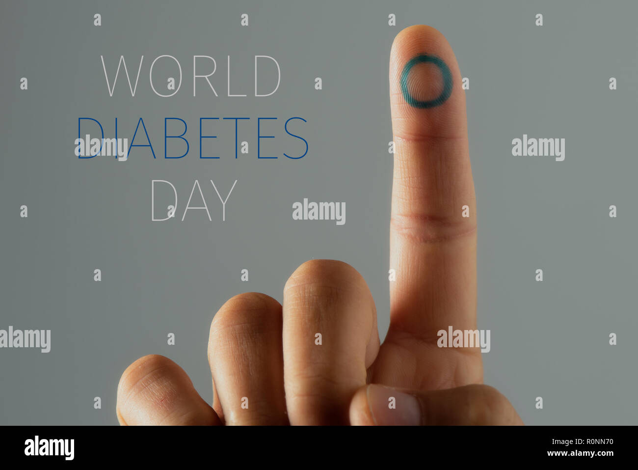 Nahaufnahme eines jungen kaukasischen Mann mit einem blauen Kreis, das Symbol des Diabetes, in seinen Zeigefinger, und der Text Weltdiabetestag Stockfoto
