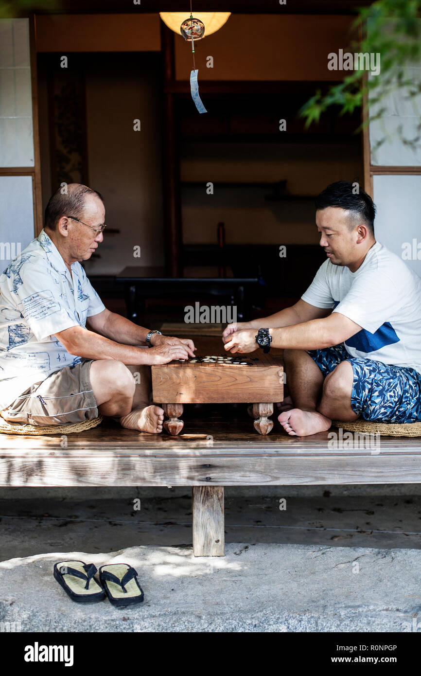 Zwei japanische Männer sitzen auf dem Boden auf der Veranda der traditionellen japanischen Haus, Spielen gehen. Stockfoto