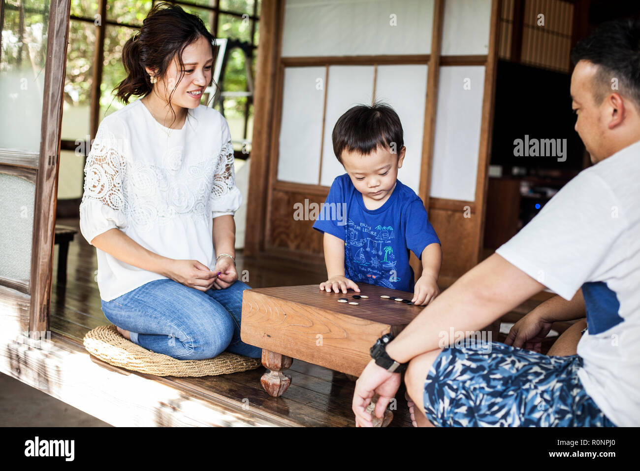 Japanische Frau, Mann und der kleine Junge sitzt auf dem Boden auf der Veranda der traditionellen japanischen Haus, Spielen gehen. Stockfoto