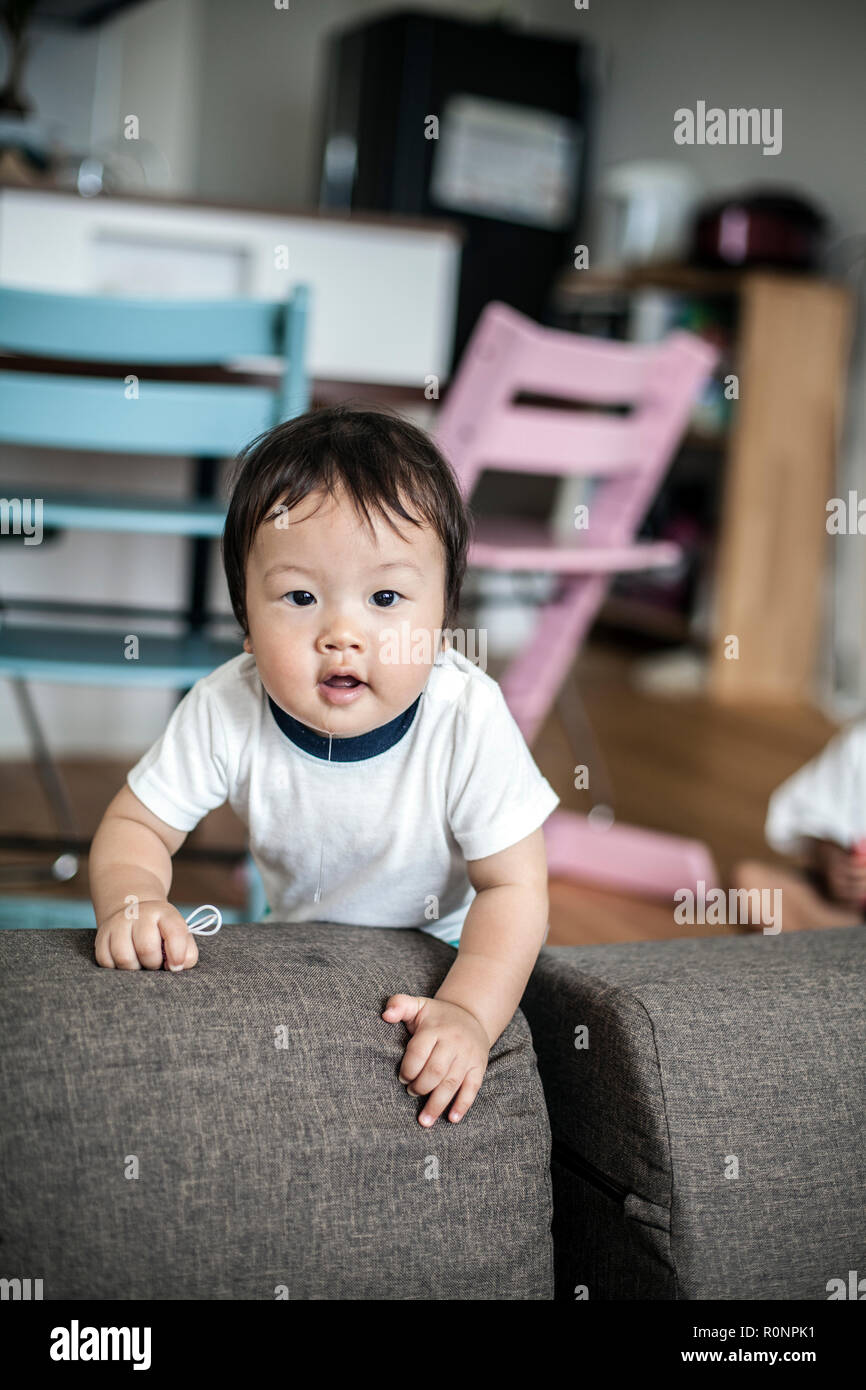 Porträt des japanischen Kleinkind stehend auf einem grauen , neugierig in die Kamera schaut. Stockfoto