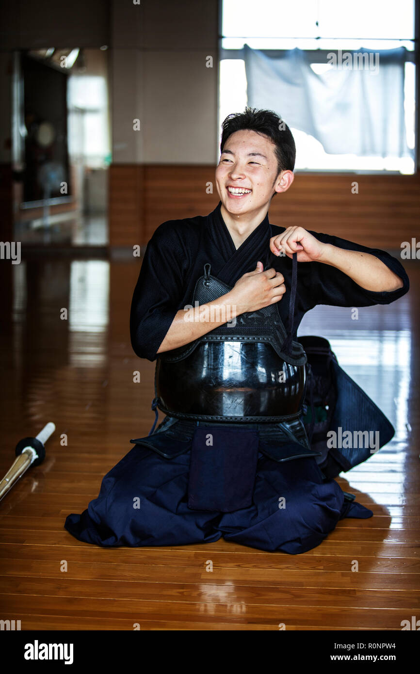 Männliche japanische Kendo Kämpfer kniet auf dem Boden, seinen Brustpanzer befestigen. Stockfoto