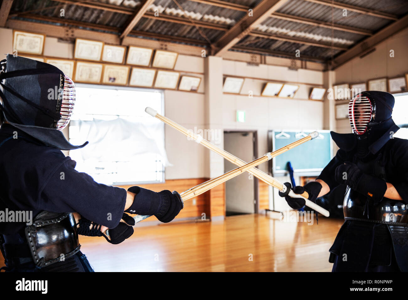 Zwei japanische Kendo Kendo Kämpfer tragen Masken üben mit Holz Schwert in der Turnhalle. Stockfoto