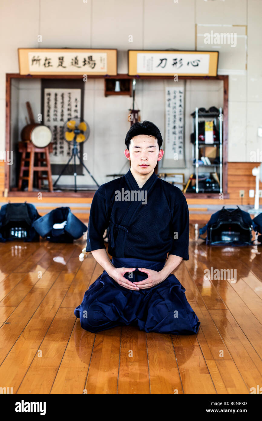 Männliche japanische Kendo Kämpfer kniend auf Holzboden, meditieren. Stockfoto