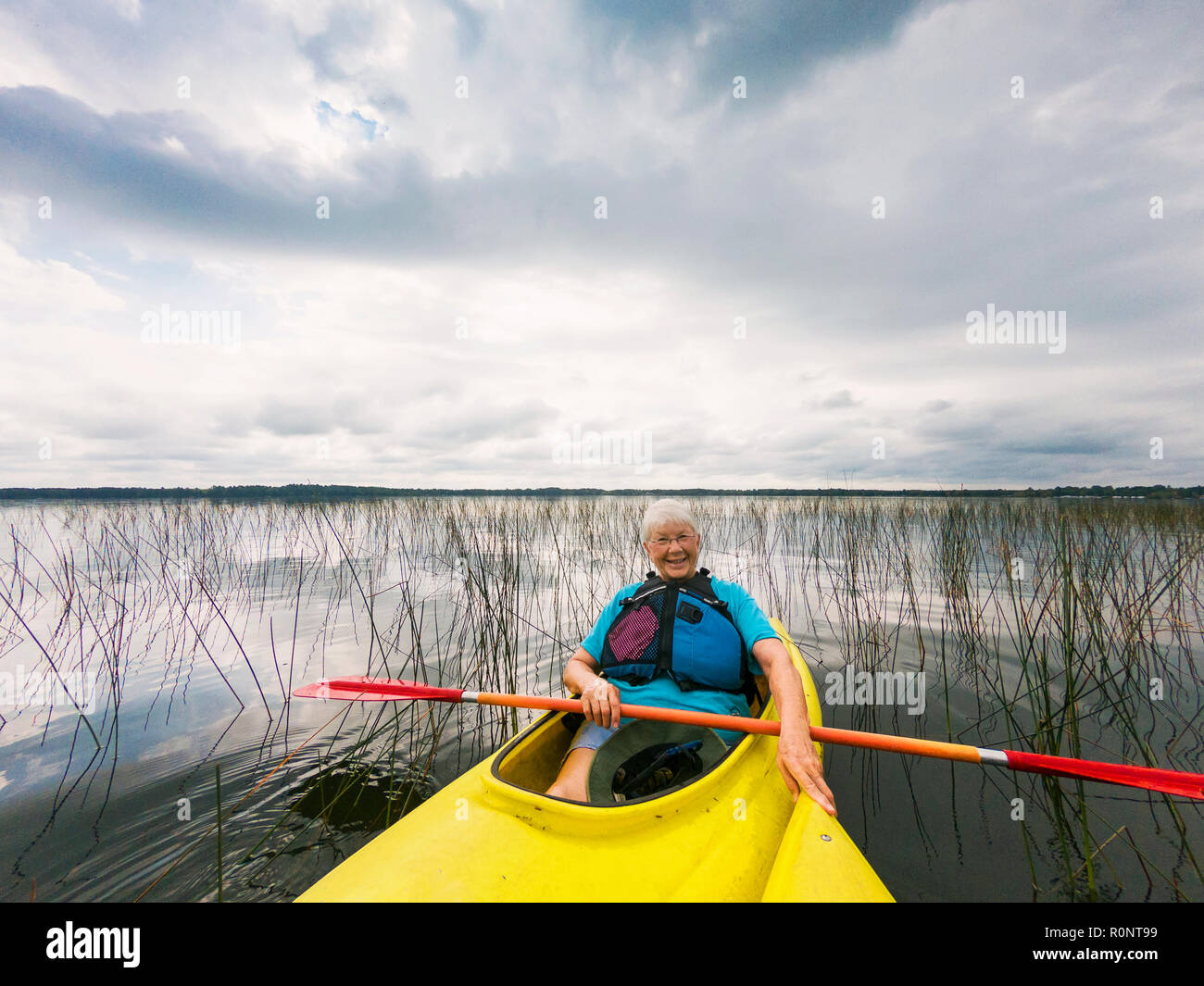 Lächelnd senior Frau Kajakfahren auf einem See, United States Stockfoto