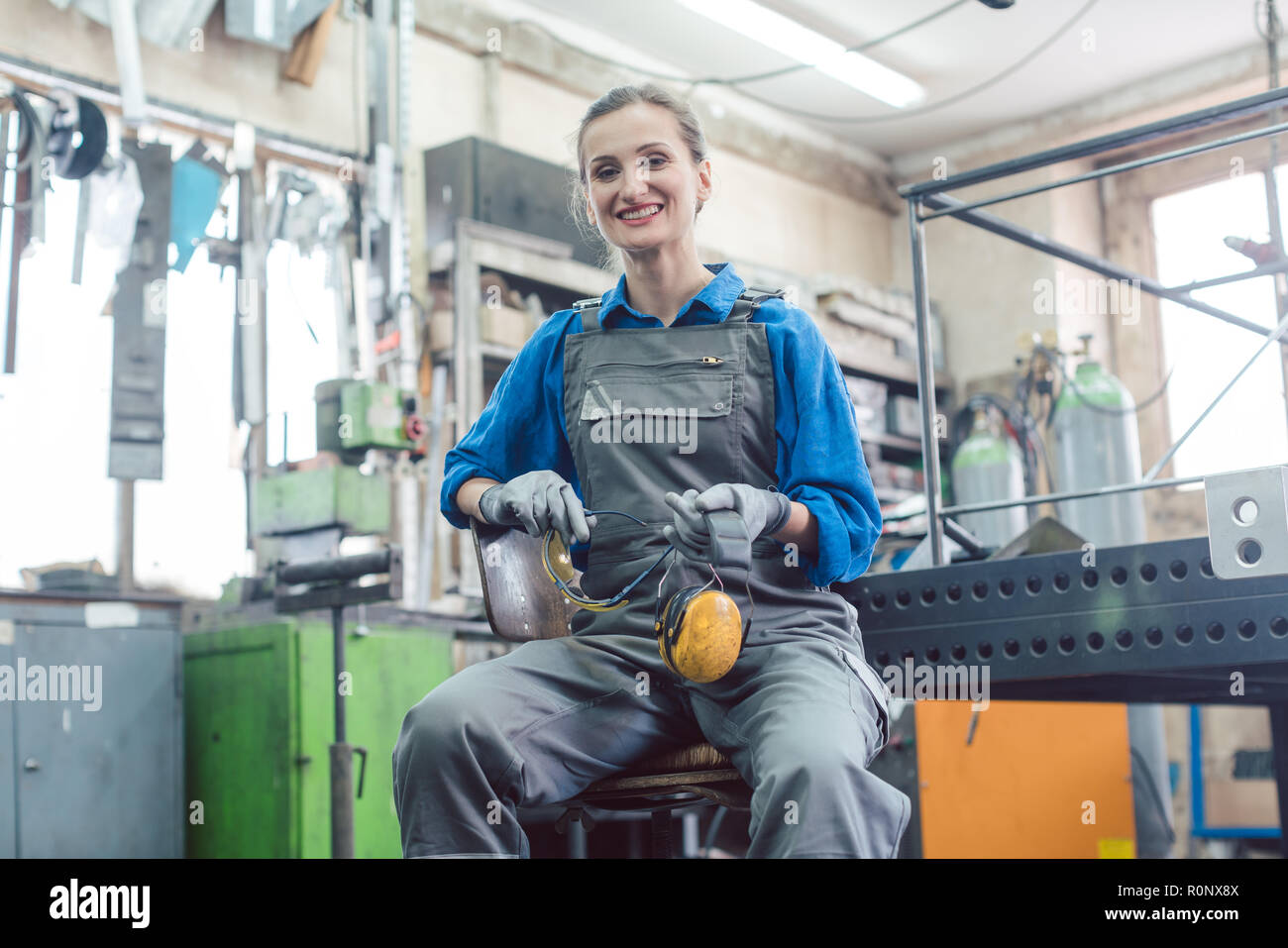 Mechanikerin sitzen in der Metallwerkstatt Suchen in die Kamera Stockfoto