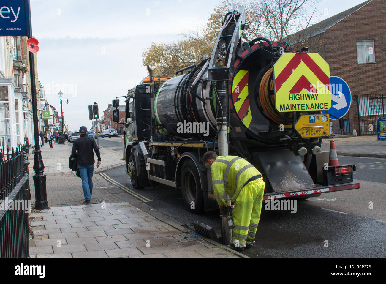 Arbeiter mit schweren Maschinen ein Abfluss in der Straße zu löschen Stockfoto