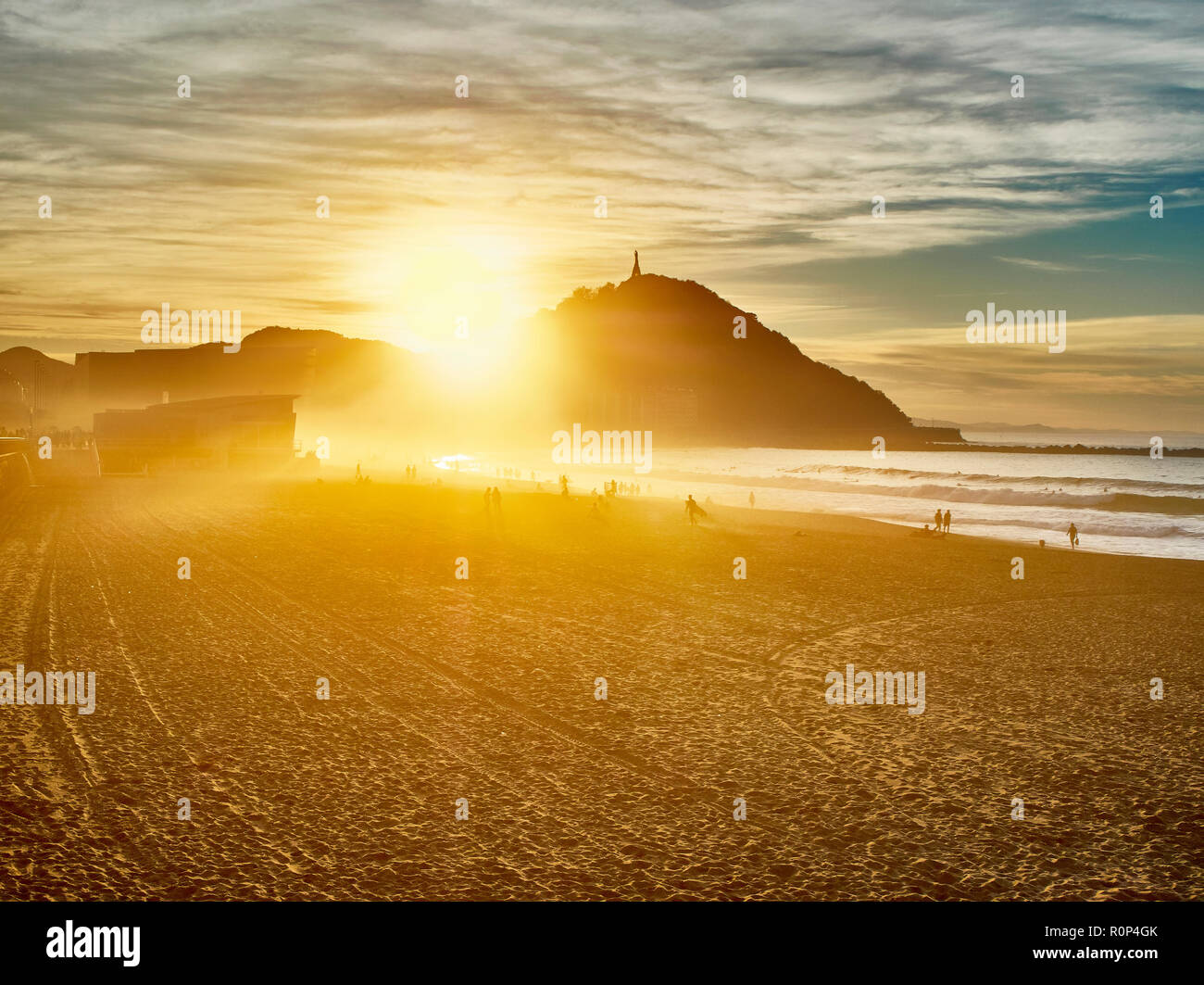 Die Sonne hinter dem Monte Urgull von San Sebastian, Baskenland, Guipuzcoa. Spanien. Blick vom Strand Zurriola. Stockfoto