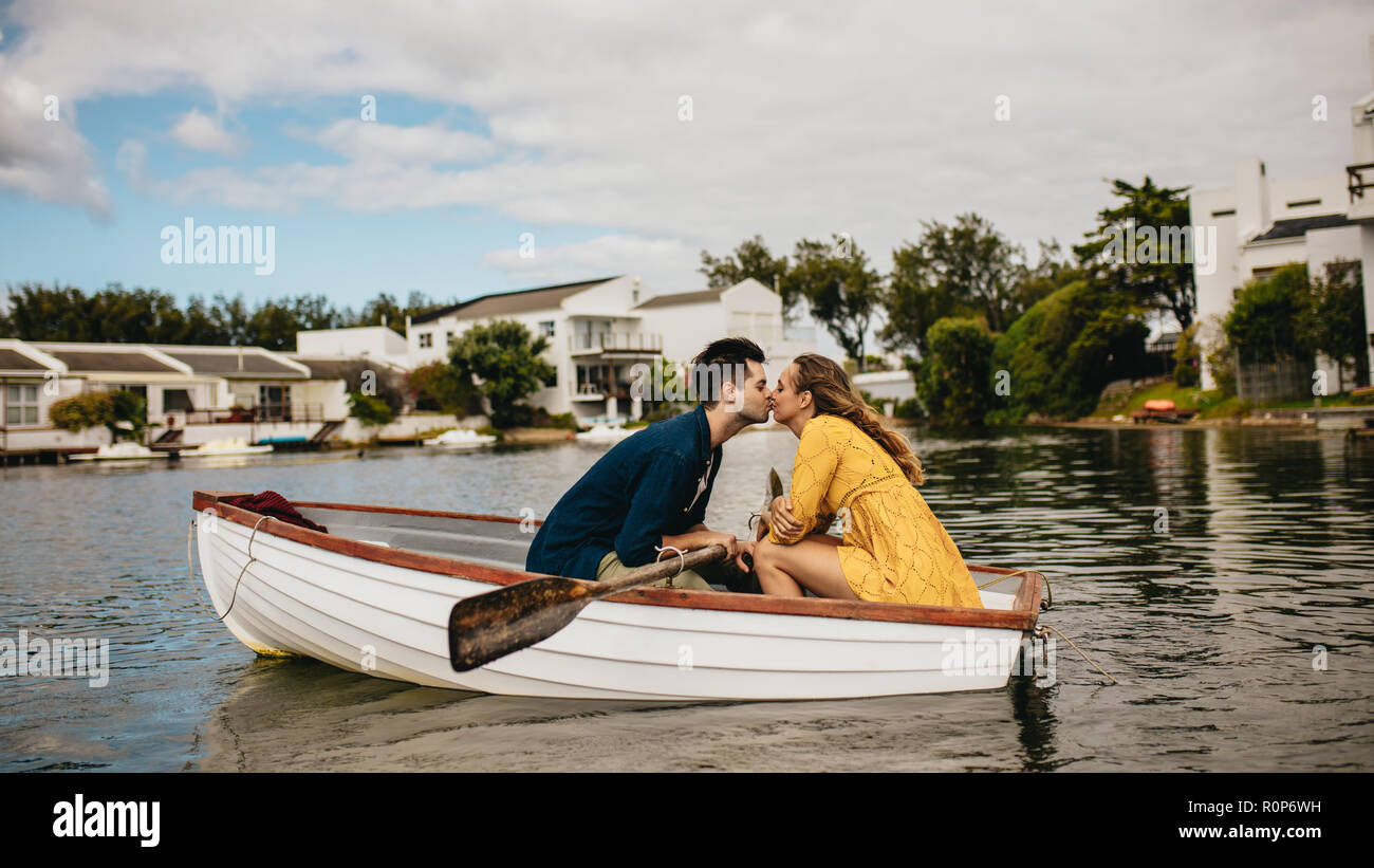 Romantisches Paar Bootfahren in einem See Zeit miteinander zu verbringen. Mann küsste seine Freundin während auf ein Datum in einem Boot sitzen. Stockfoto