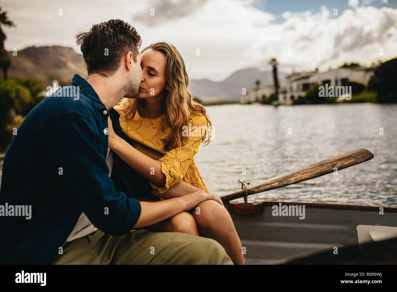 Junges Paar auf ein romantisches Date sitzen in einem Boot und Küssen. Verliebtes Paar in einem Boot sitzen, Küssen mit Augen geschlossen halten. Stockfoto
