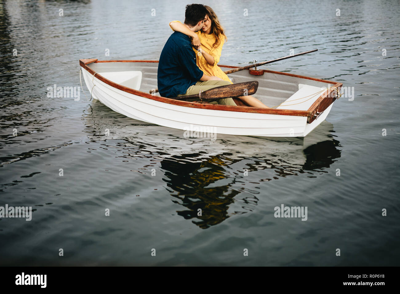 Junges Paar auf ein Datum in einem Boot jeder andere Holding sitzen. Frau küssen ihr Freund ihn in die Arme, während auf einem Boot. Stockfoto