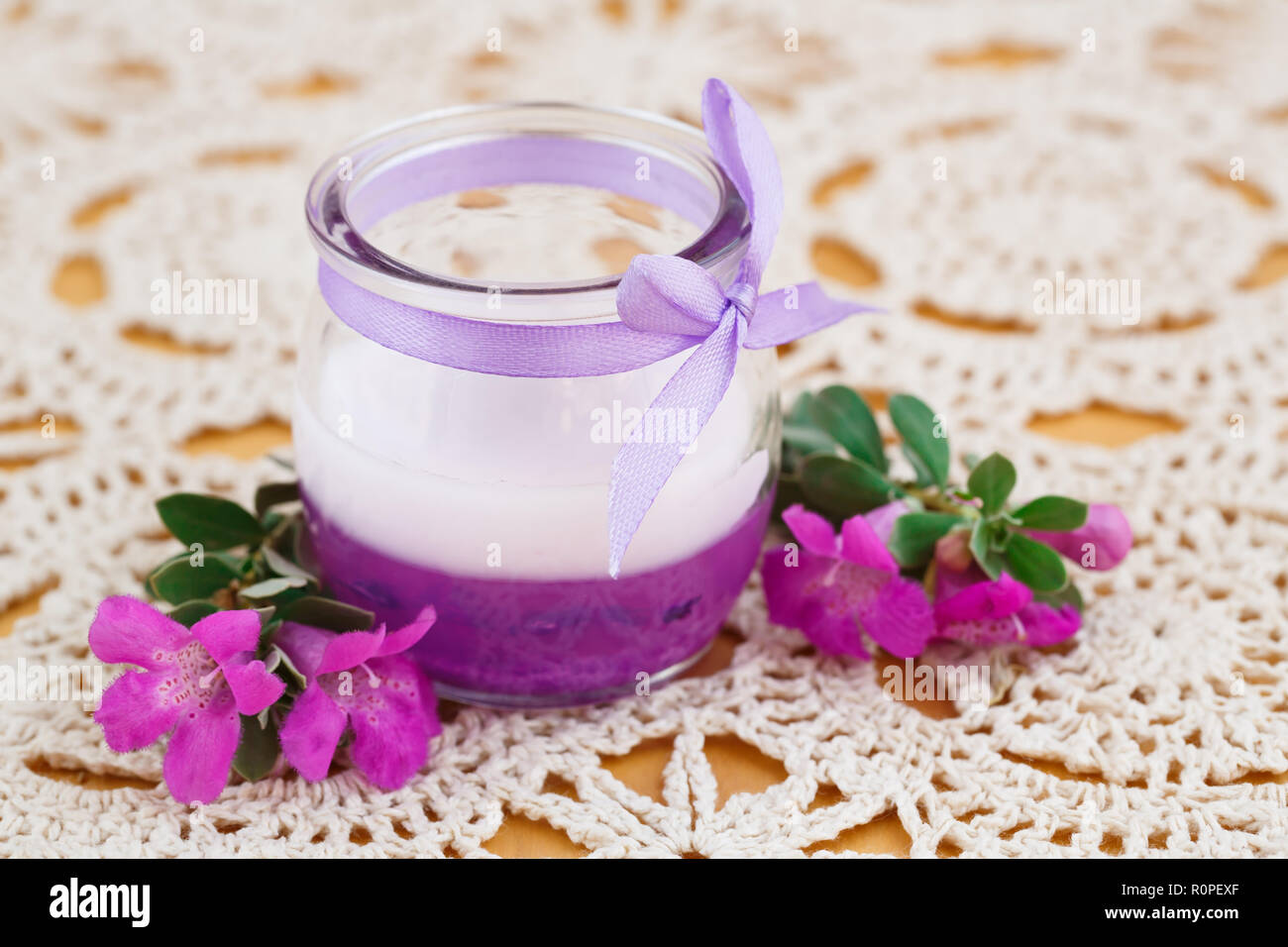 Schöne Kerze und rosa Blumen auf Hintergrund Tuch. Stockfoto