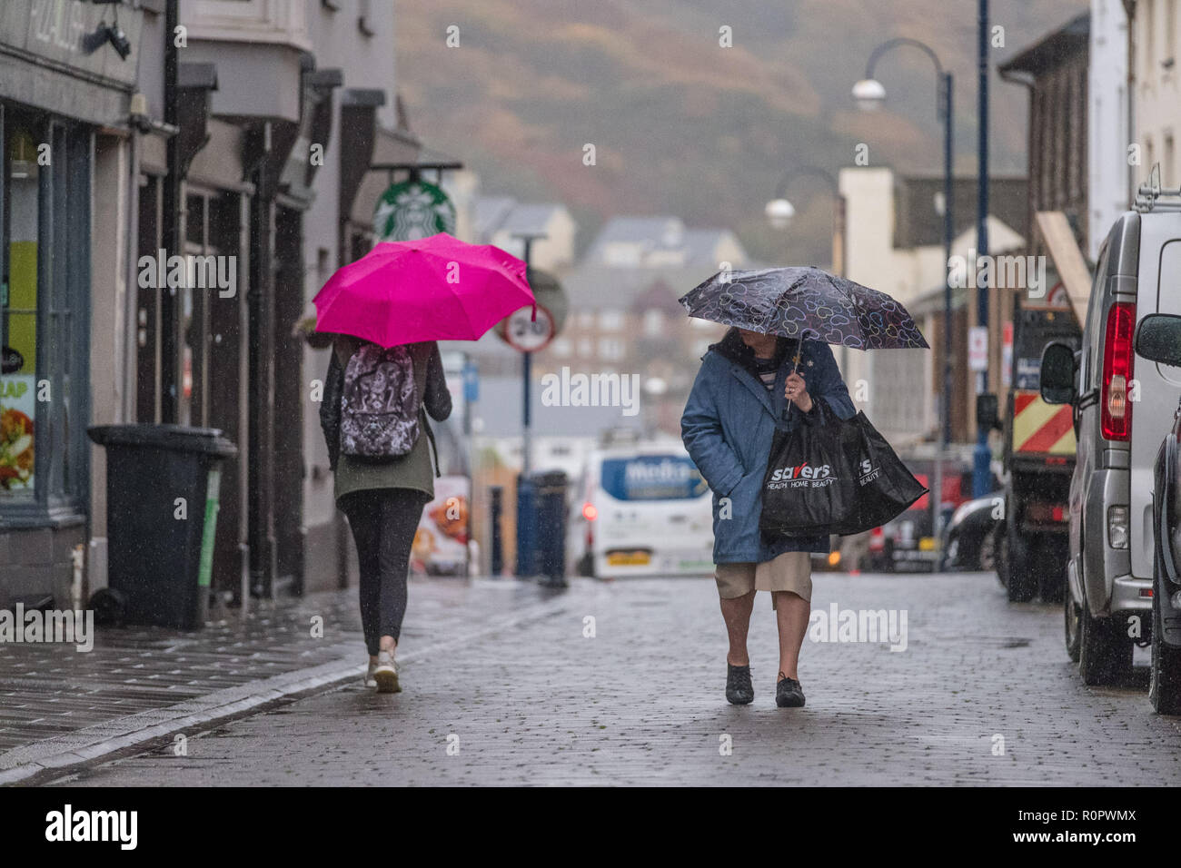 Aberystwyth, Wales, UK. 7. November 2018. UK Wetter: Menschen zu Fuß im Regen auf einer sehr nass, aber mild, morgen in Aberystwyth. Das Met Office hat eine gelbe Warnmeldung für Regen und Überschwemmungen, die viel von Süd und West Wales heute morgen, mit einer weiteren Warnung für mehr Regen und Sturm Winde für den gleichen Bereich am Freitag gab auch ausgestellt. Foto: Keith Morris/Alamy leben Nachrichten Stockfoto