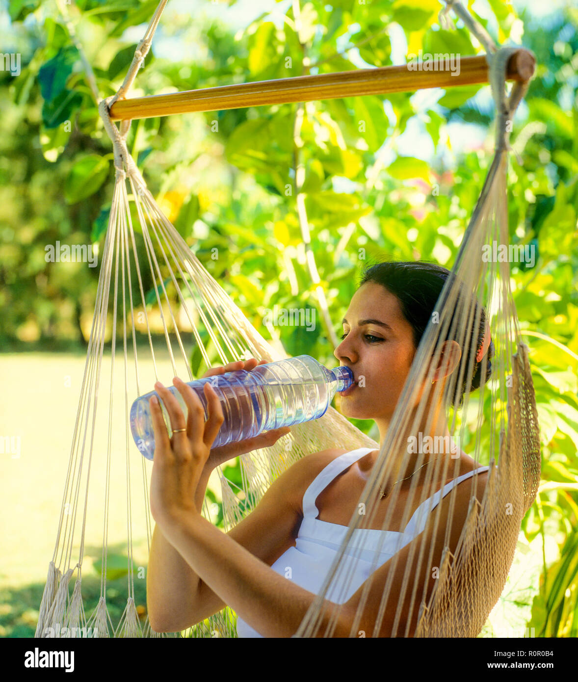 Junge Frau trinkt Mineralwasser aus Plastikflaschen, tropischen Garten, Guadeloupe, Französisch Westindien, Stockfoto